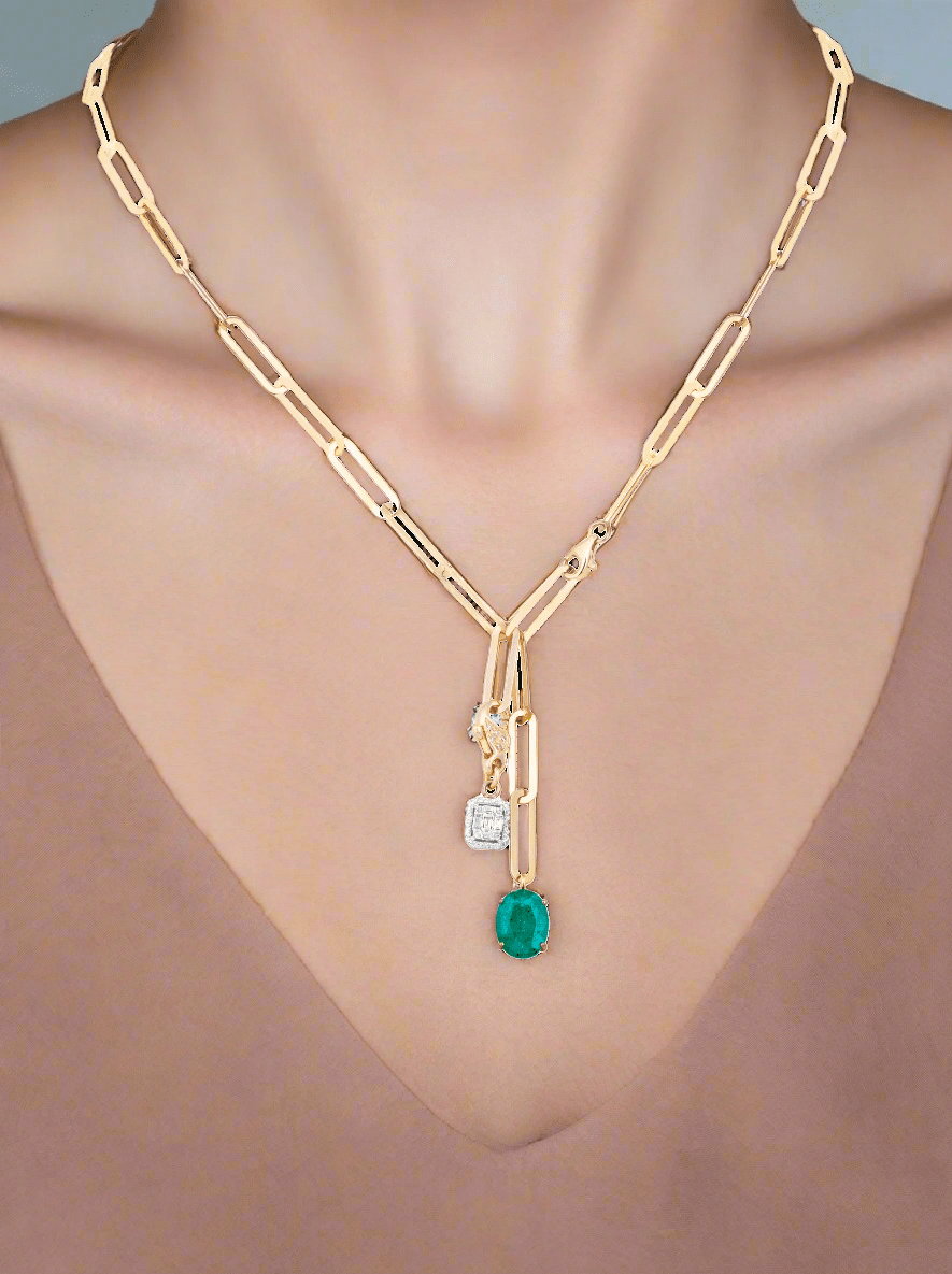 Gold necklace with emerald and diamond pendant on a white background